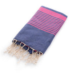 Folded Miami Beach Fouta Turkish towel in navy blue with vibrant fuchsia stripes and tassels